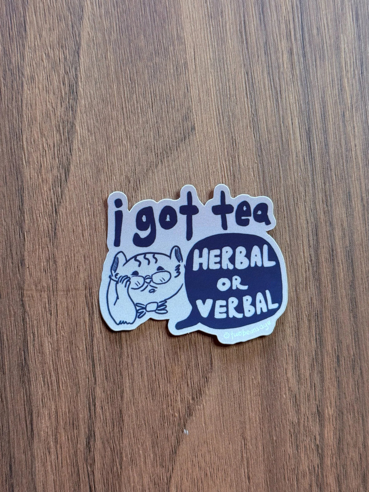 A die-cut sticker featuring a cartoon cat and the text 'i got tea' and 'HERBAL OR VERBAL'