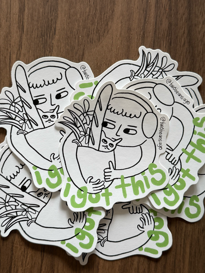 A pile of die-cut stickers featuring a black and white line art illustration of a person holding a rabbit, with green text reading 'I got this' 